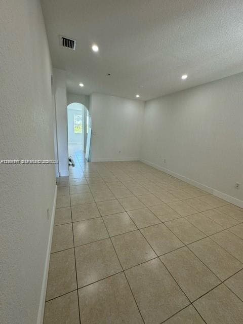 Spacious interior room featuring neutral wall finishes, recessed ceiling lighting, and tile flooring throughout