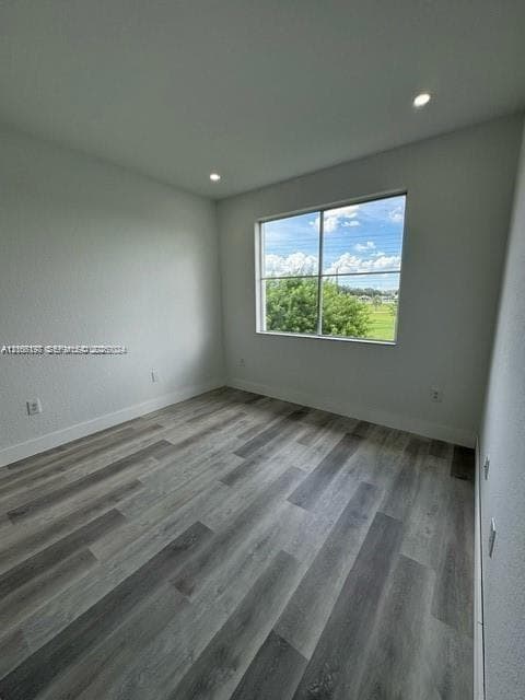Neutral wall finishes, recessed ceiling lighting, and expansive wood-finish flooring