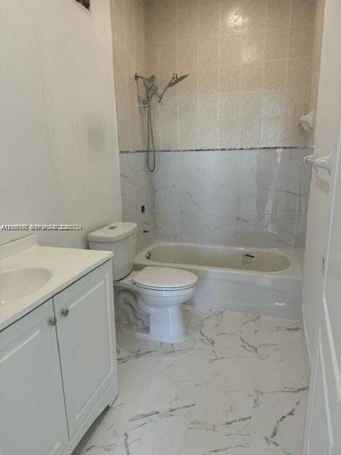 Bathroom featuring white vanity with integrated sink, porcelain tile flooring with veined detailing, tub-shower combination with tiled surround, and chrome adjustable-head shower fixture