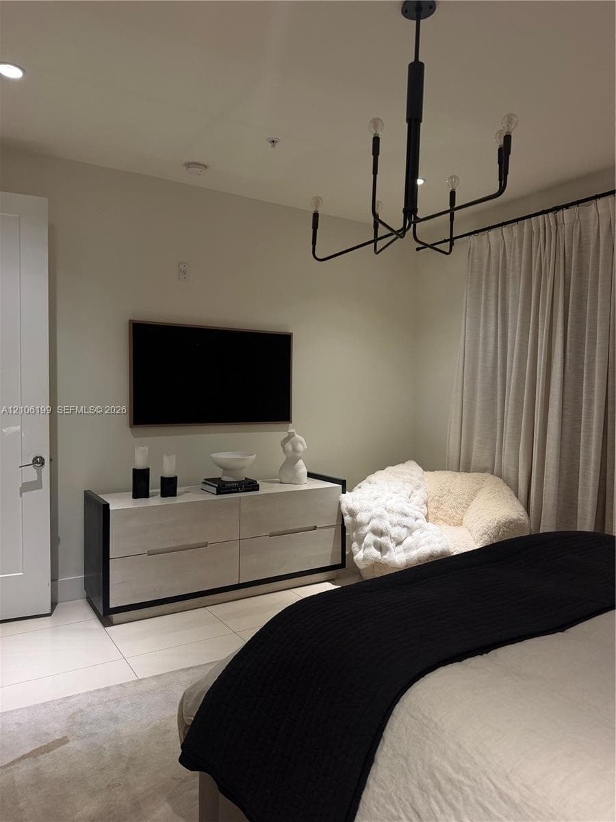 Modern matte black chandelier, large-format tile flooring, and clean-lined solid door