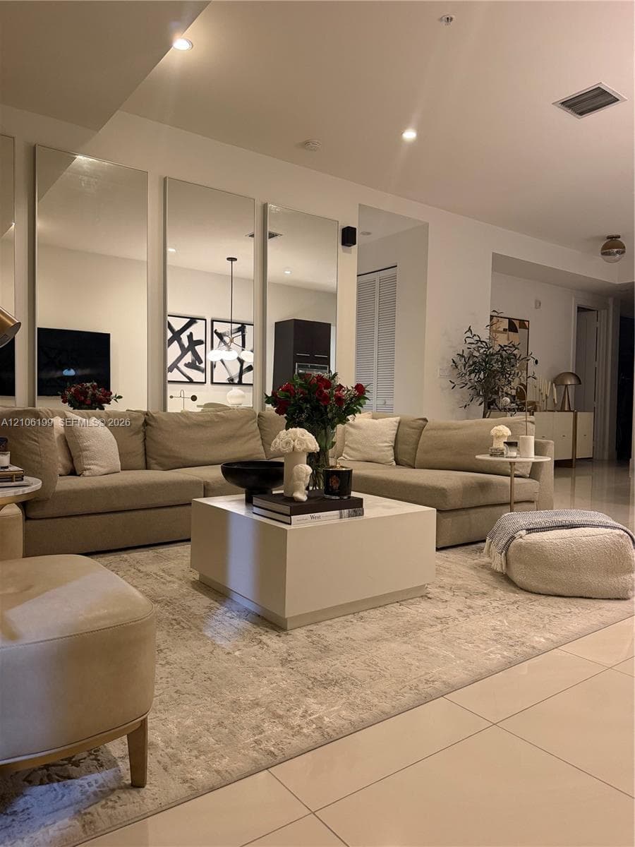 Living area featuring floor-to-ceiling wall mirrors, recessed lighting, and large-format tile flooring