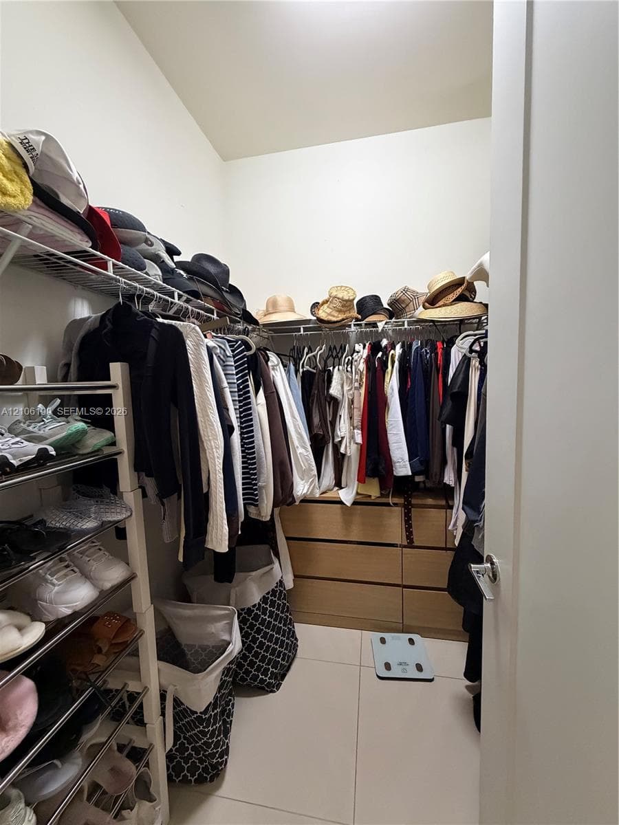 Walk-in closet featuring light-toned cabinetry with six pull-out drawers, white tile flooring, and integrated metal wire shelving