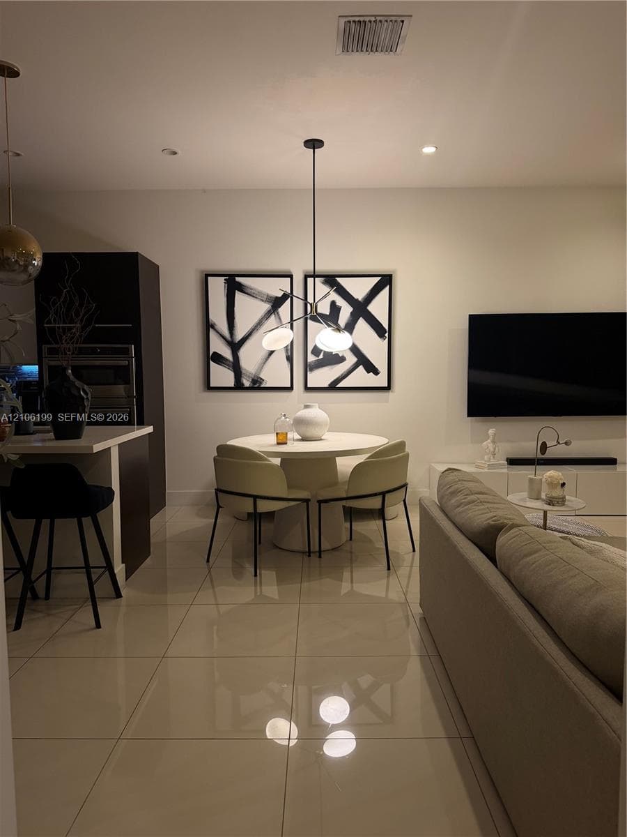Polished large-format tile flooring, multi-light contemporary chandelier, built-in dark cabinetry, and recessed lighting