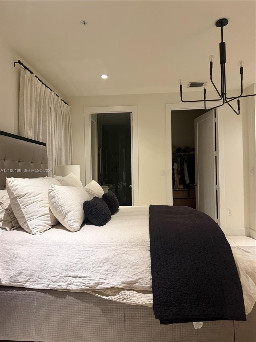Minimalist space featuring a matte black multi-arm chandelier, recessed ceiling lighting, and smooth-finish flooring