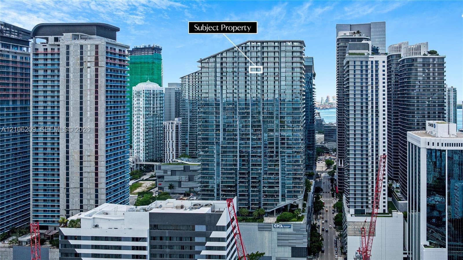 High-rise residential building featuring floor-to-ceiling glass windows and multiple private balconies, situated within a dense urban metropolitan center