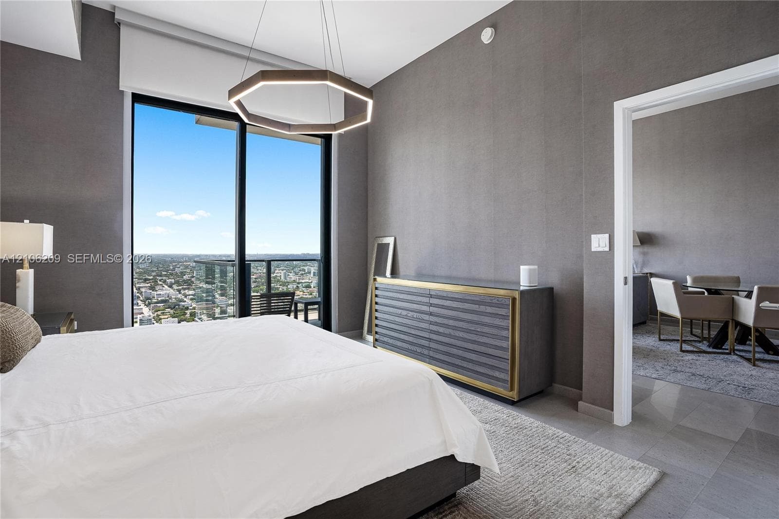 Floor-to-ceiling windows, private balcony, geometric LED pendant light, stone-finish tile flooring, and textured wall finish
