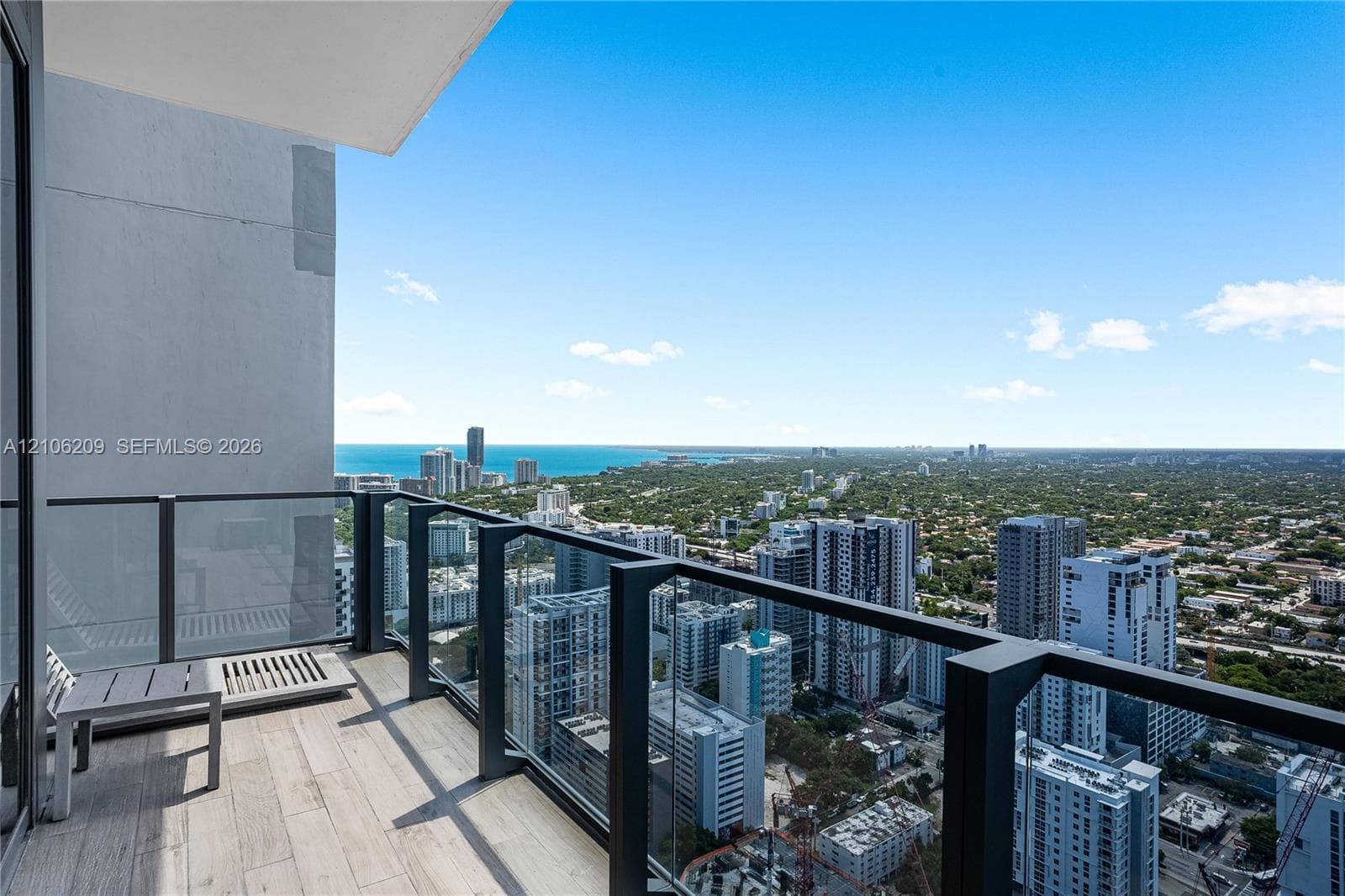 Private balcony featuring wood-finish tile flooring and a glass panel railing with metal framing