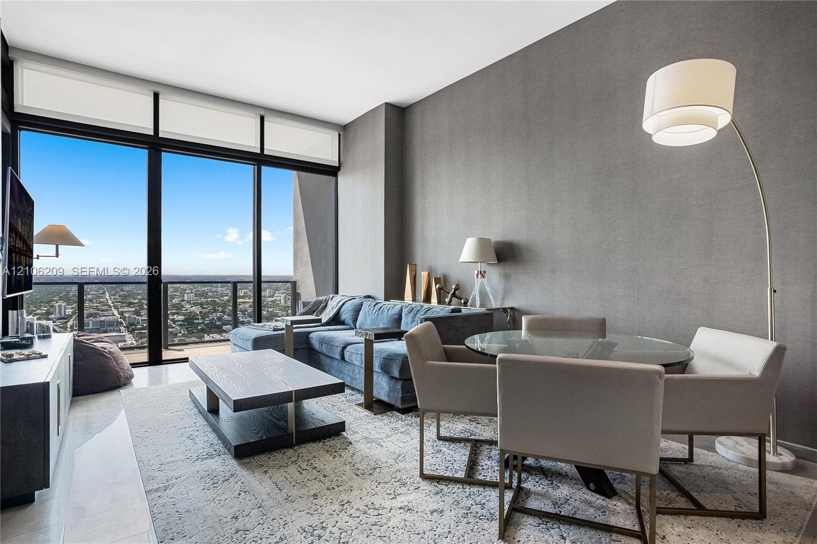 Floor-to-ceiling windows with expansive exterior scenery, textured grey accent wall, and polished stone-finish flooring