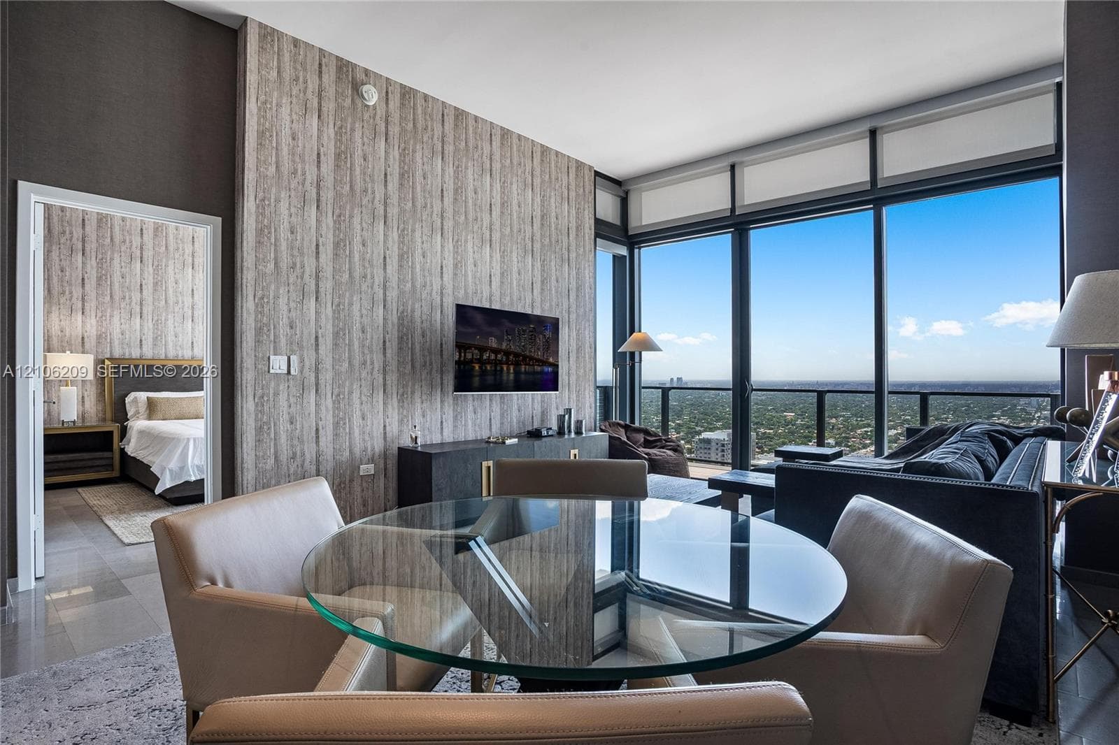 Floor-to-ceiling glass windows, textured accent wall, polished tile flooring, and integrated black balcony railing