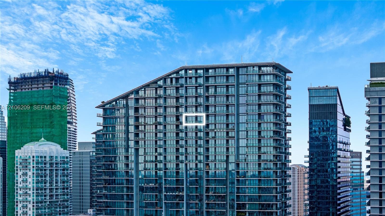 High-rise architectural exterior featuring a glass-facade curtain wall, tiered roofline, and private recessed balconies