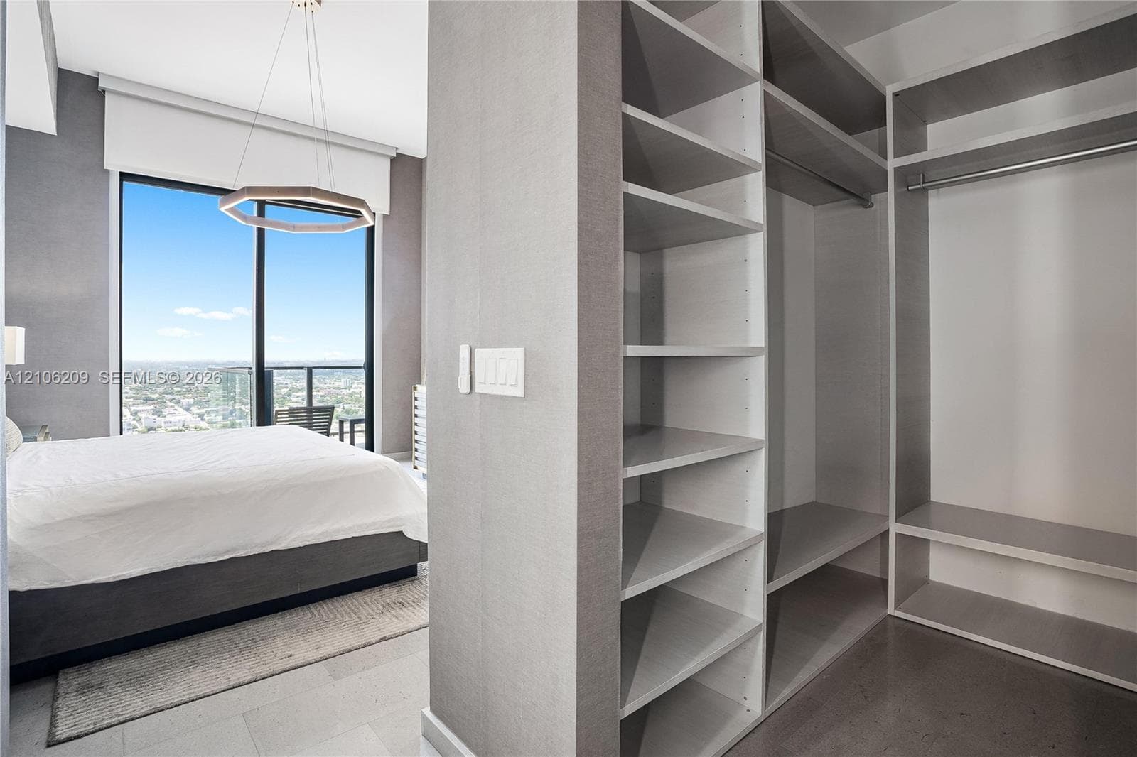 Custom walk-in closet featuring built-in shelving and integrated garment rods, floor-to-ceiling glass wall, recessed lighting, and geometric pendant fixture