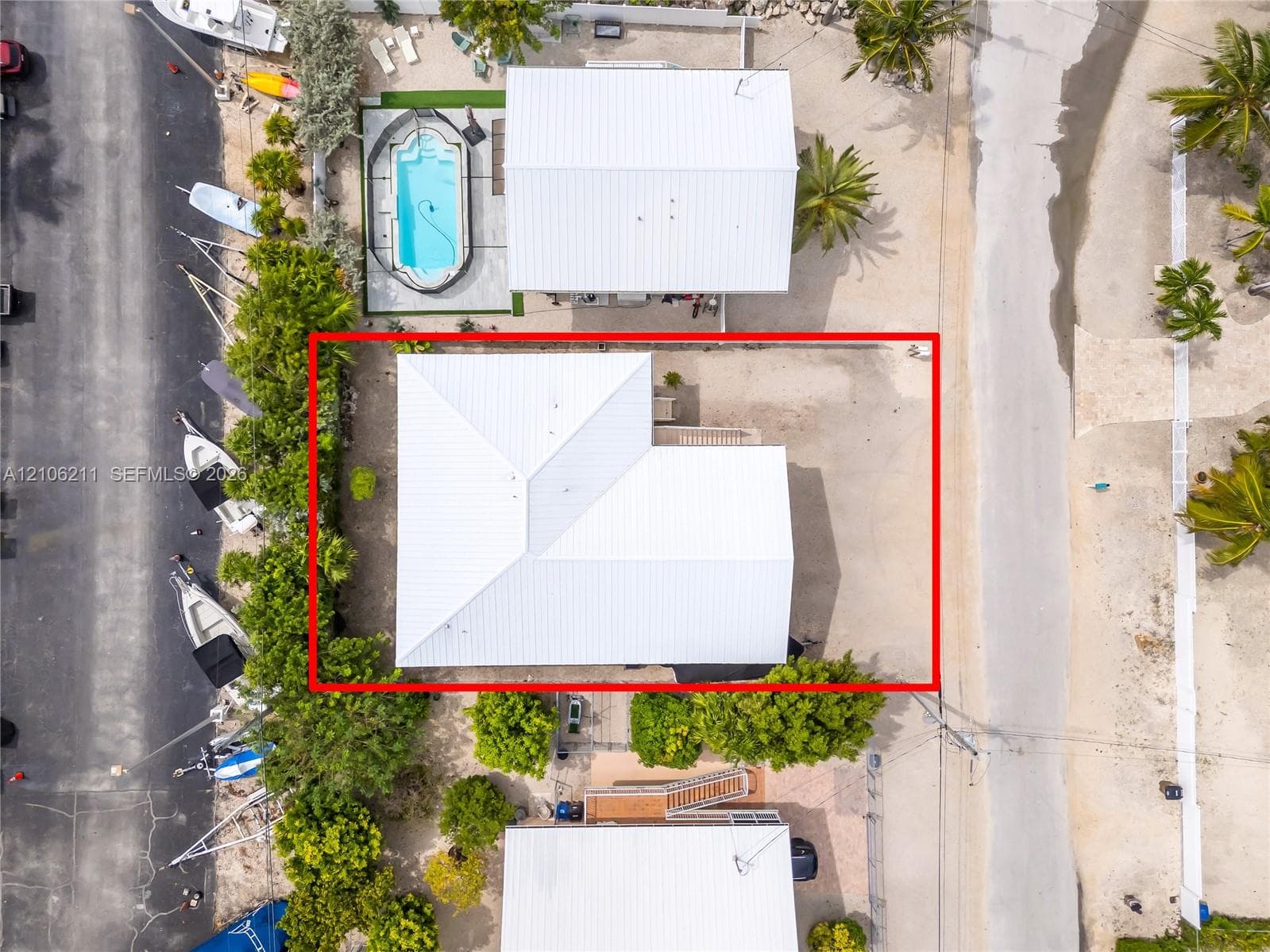 Aerial perspective of property featuring a metal roof and mature tropical landscaping