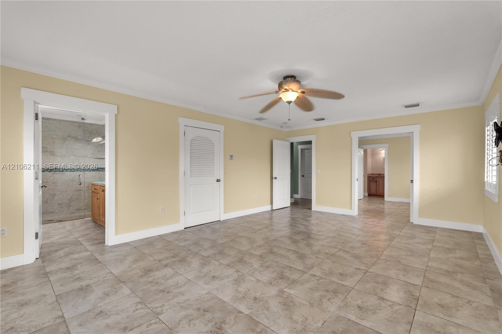 Spacious room featuring tile flooring, a central ceiling fan with integrated lighting, recessed lighting, and multiple arched door frames