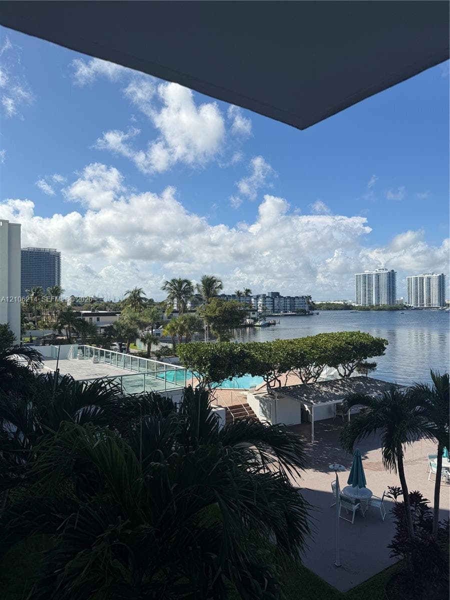 Elevated exterior perspective featuring a swimming pool, paved sundeck, pergola-covered seating area, and waterfront access