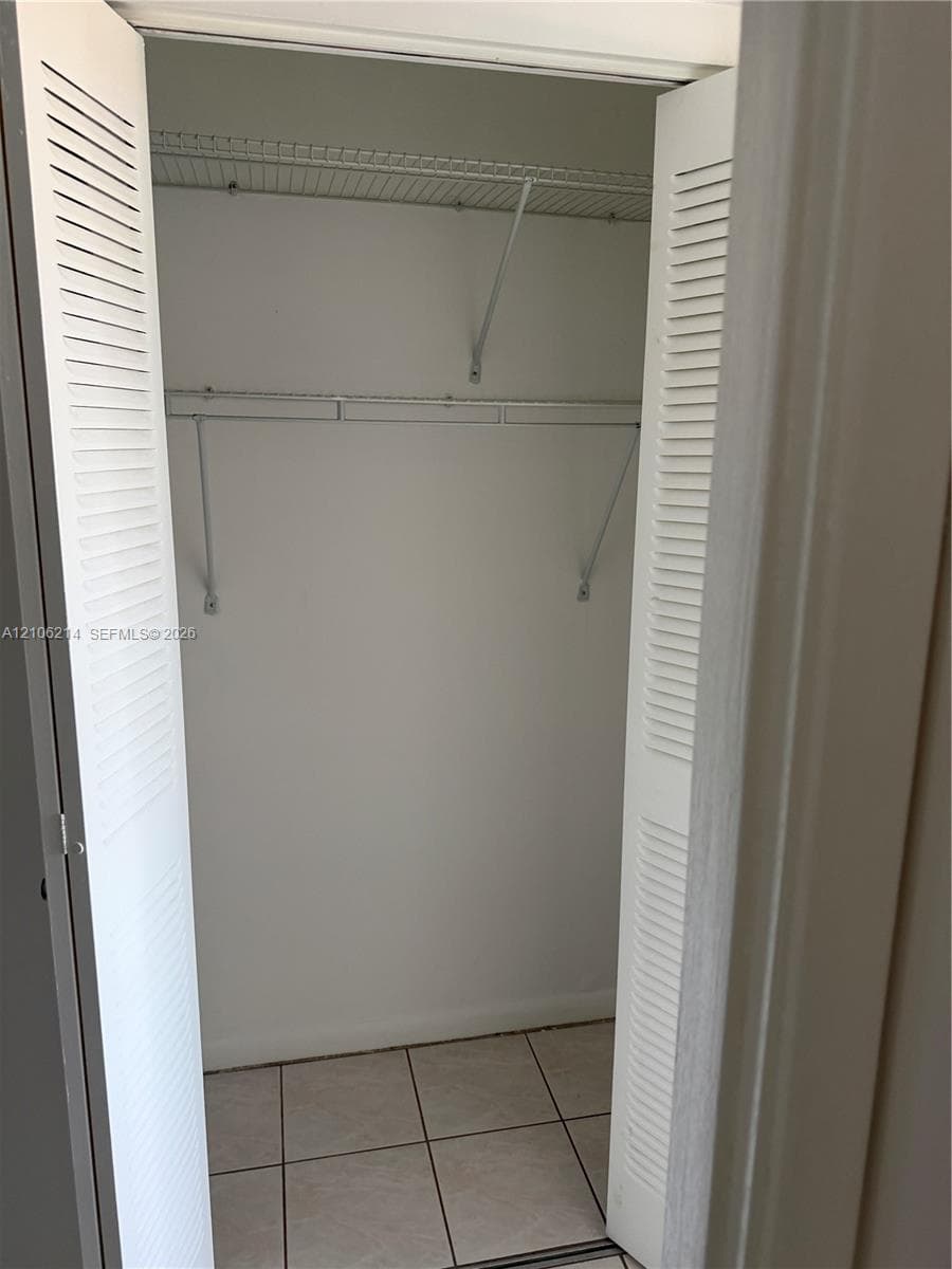 Closet featuring white louvered bifold doors, tile flooring, and built-in wire shelving