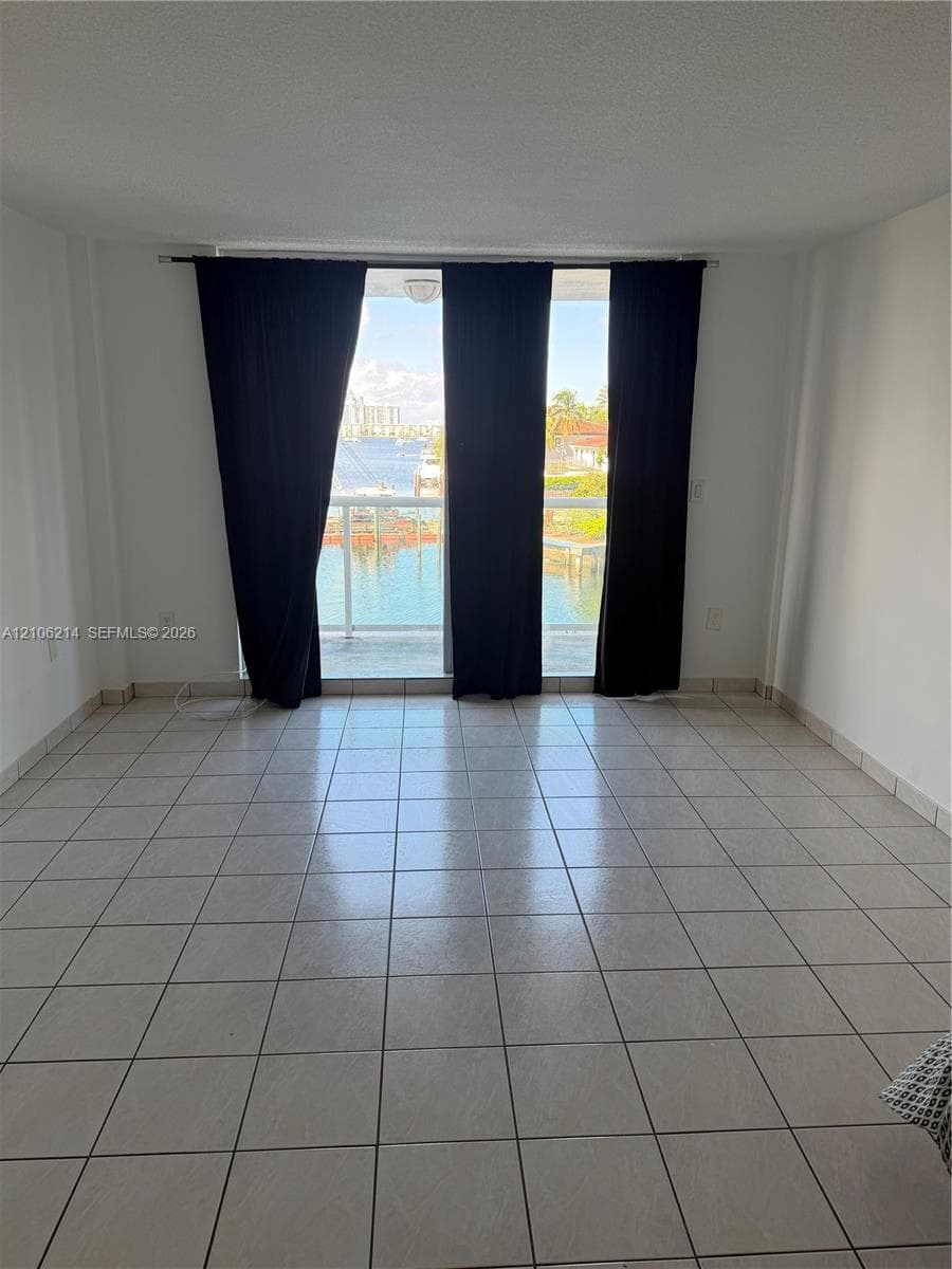 Interior space featuring ceramic tile flooring, floor-to-ceiling glass sliding doors, and a private balcony overlooking the water