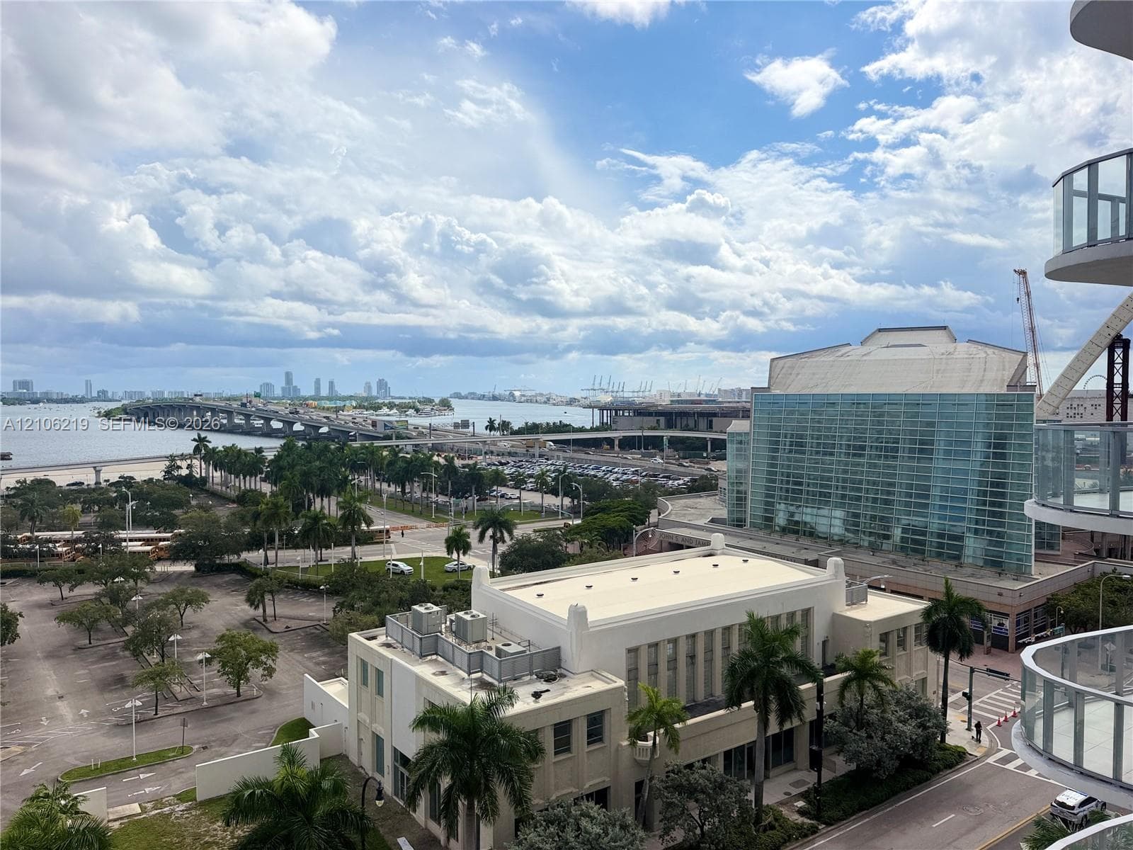 Elevated balcony featuring a glass panel railing and panoramic vistas of the waterfront, cityscape, and surrounding infrastructure