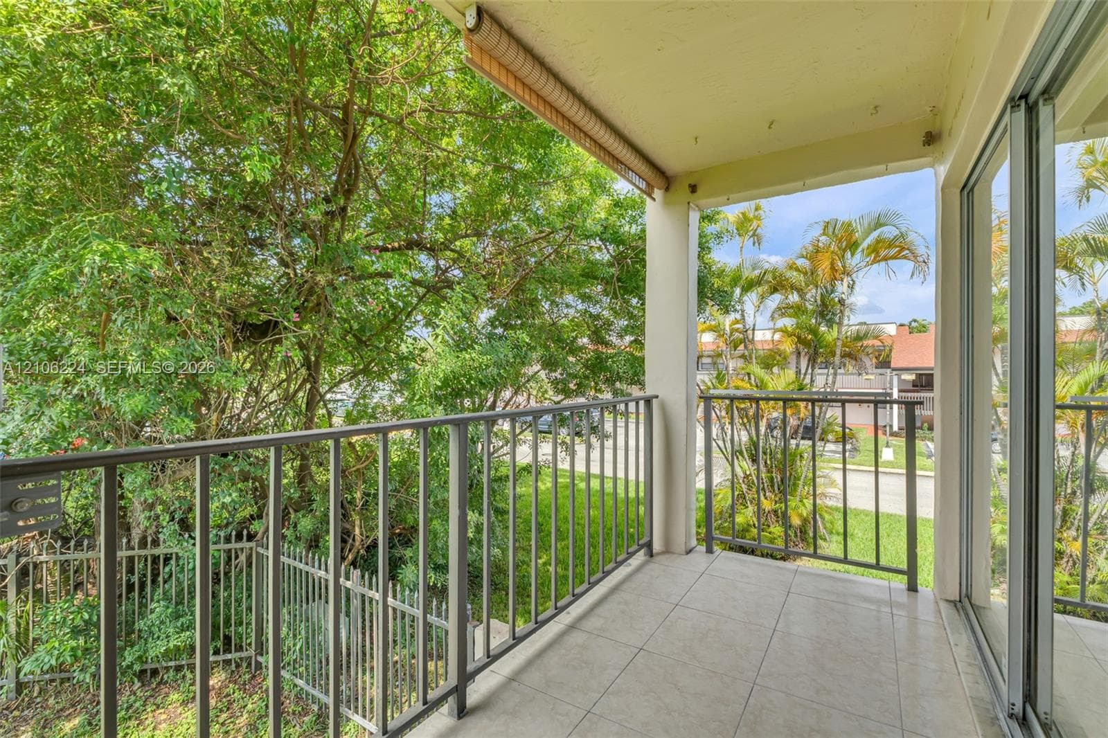 Covered balcony featuring tile flooring, metal railings, and a retractable fabric awning