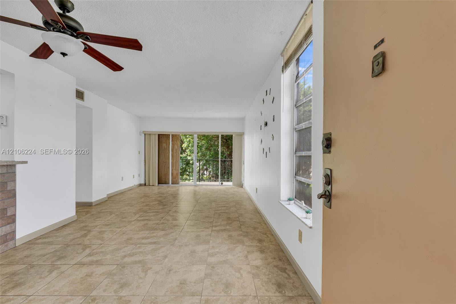 Interior space featuring ceramic tile flooring, a multi-blade ceiling fan, vertical window blinds, and sliding glass doors with exterior access