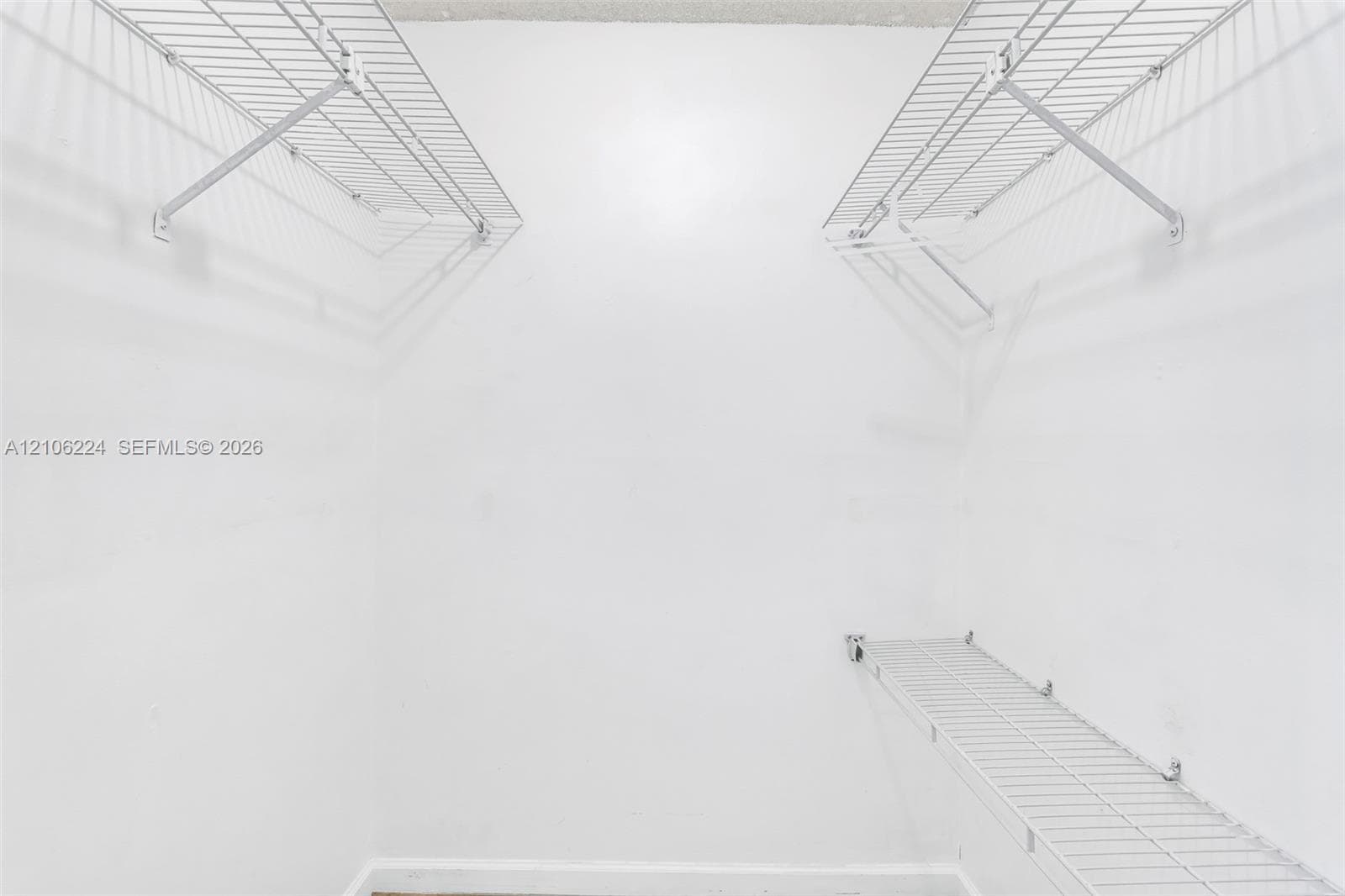 Walk-in closet featuring white walls and tiered white wire shelving