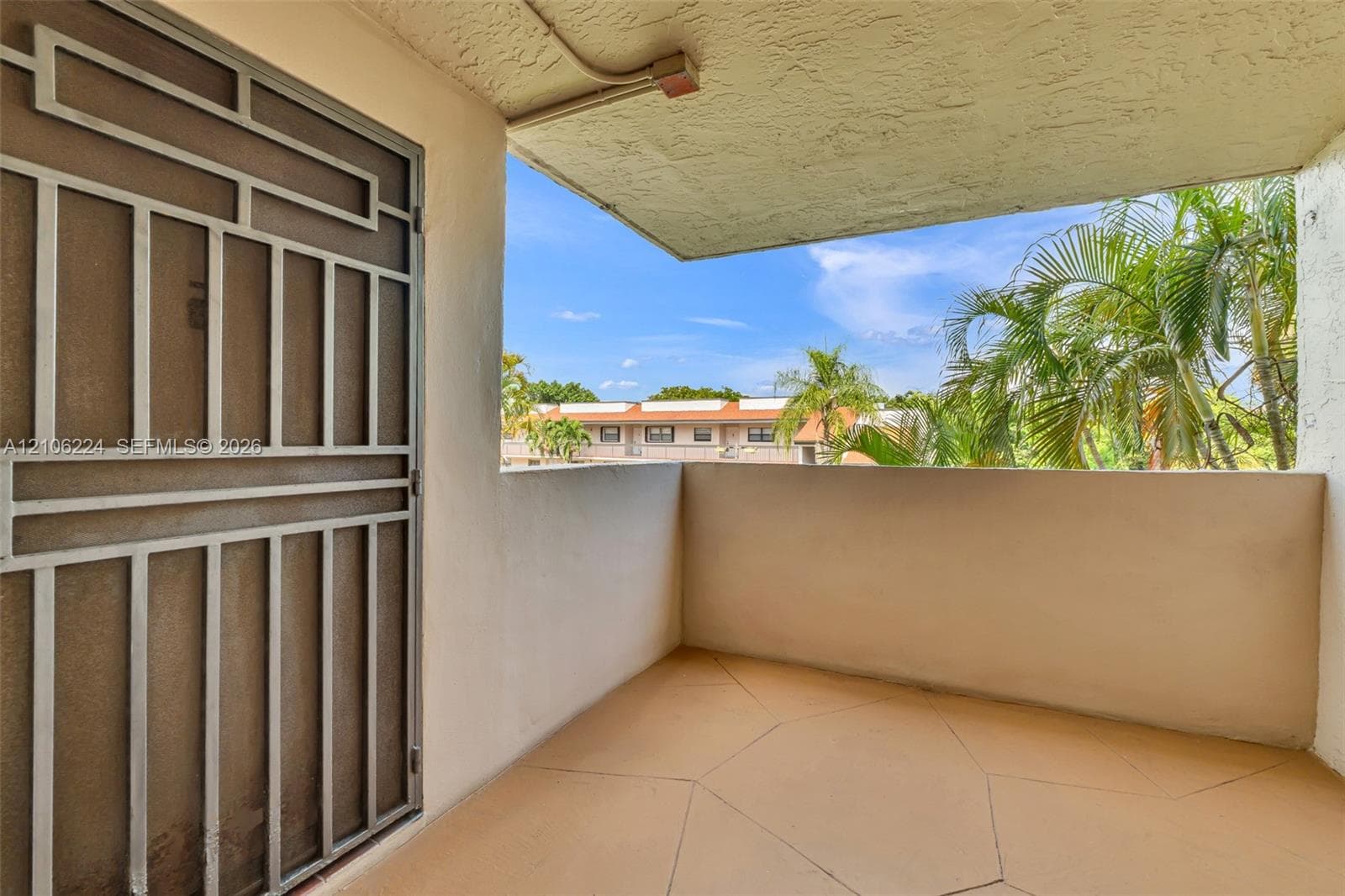 Covered balcony featuring concrete flooring, a stucco ceiling, solid walls, and a metal security screen door
