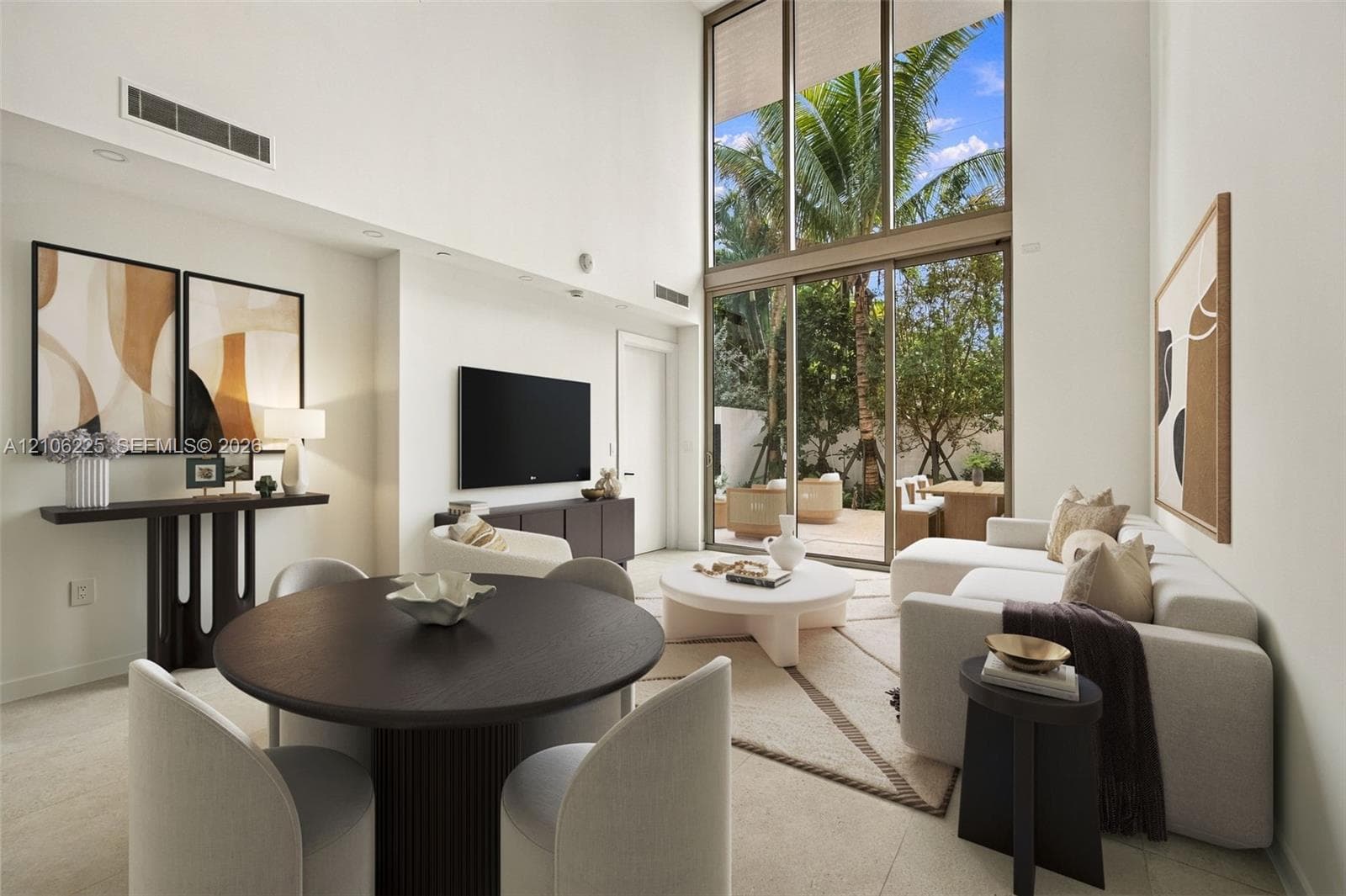 Double-height ceiling, floor-to-ceiling windows, sliding glass door, neutral stone-finish flooring, and recessed lighting