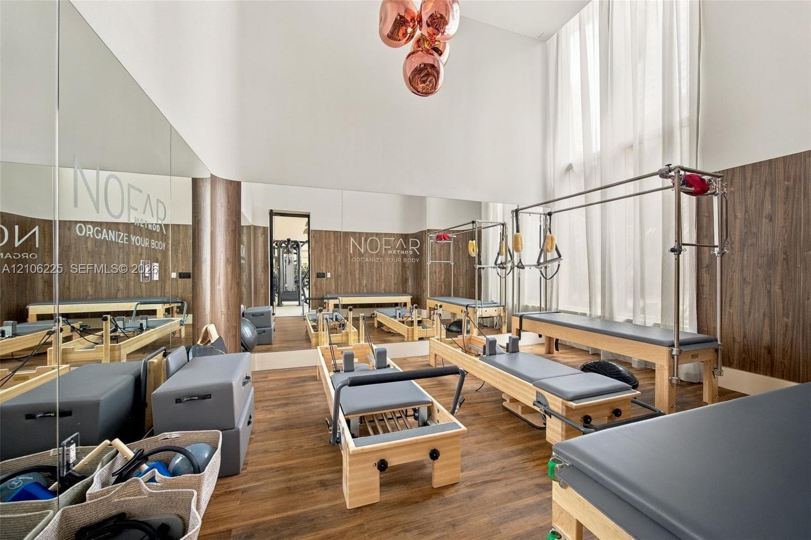 Double-height ceilings, floor-to-ceiling mirror wall, wood-finish wall paneling, wood-finish flooring, and multi-globe pendant light fixture