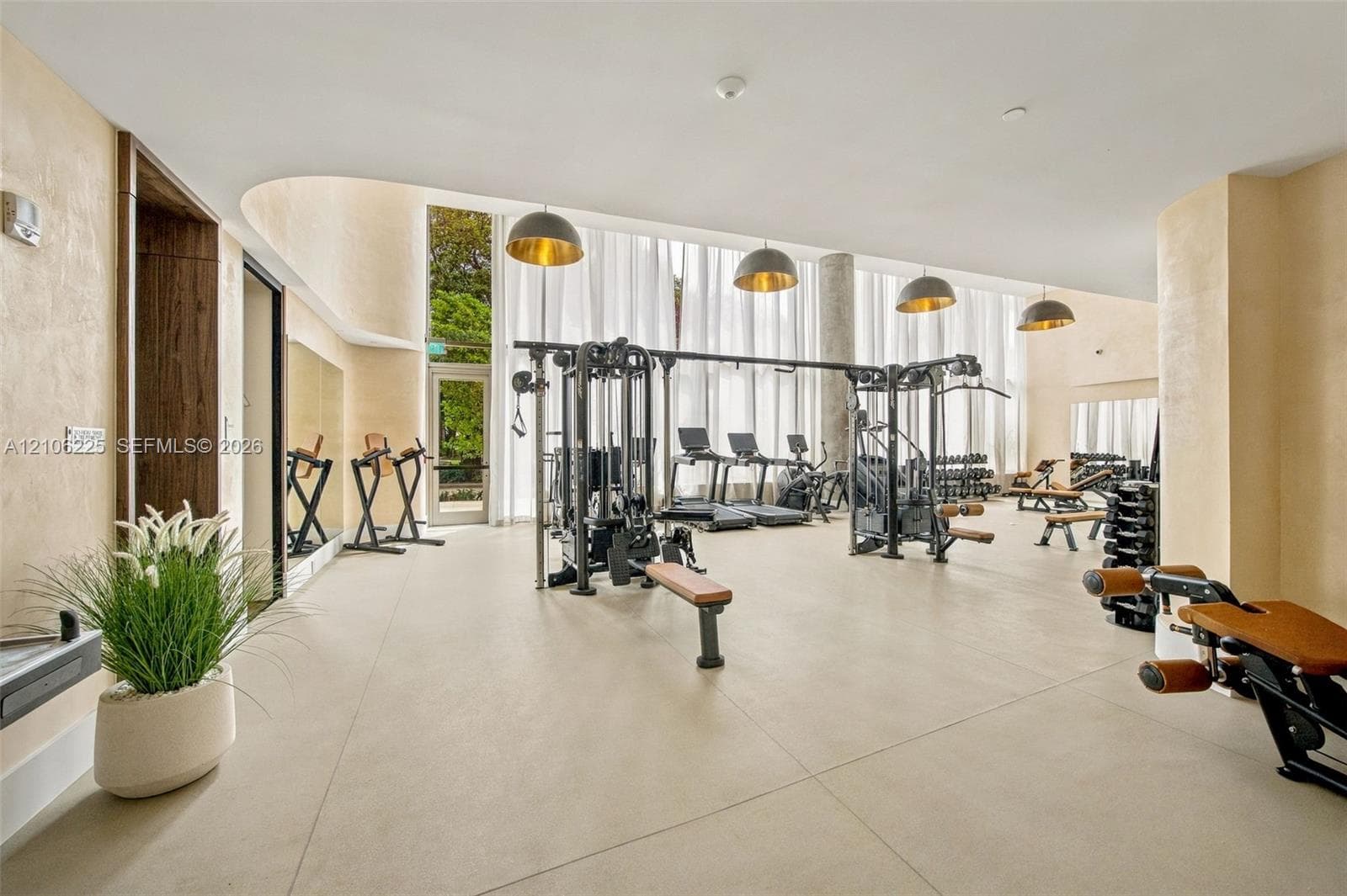 Fitness center featuring floor-to-ceiling windows, large-format tile flooring, curved architectural detailing, and recessed dome pendant lighting