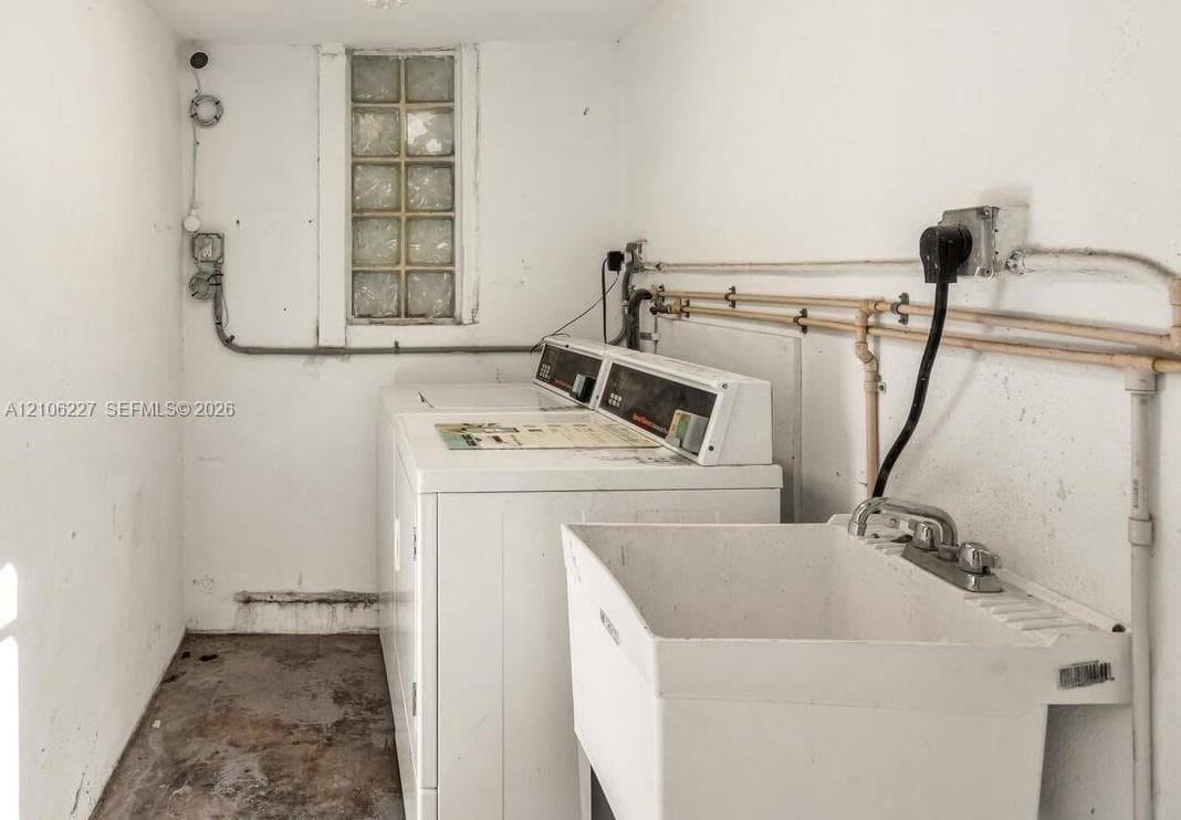 Utility area featuring a glass block window and a wall-mounted utility basin with a dual-handle faucet