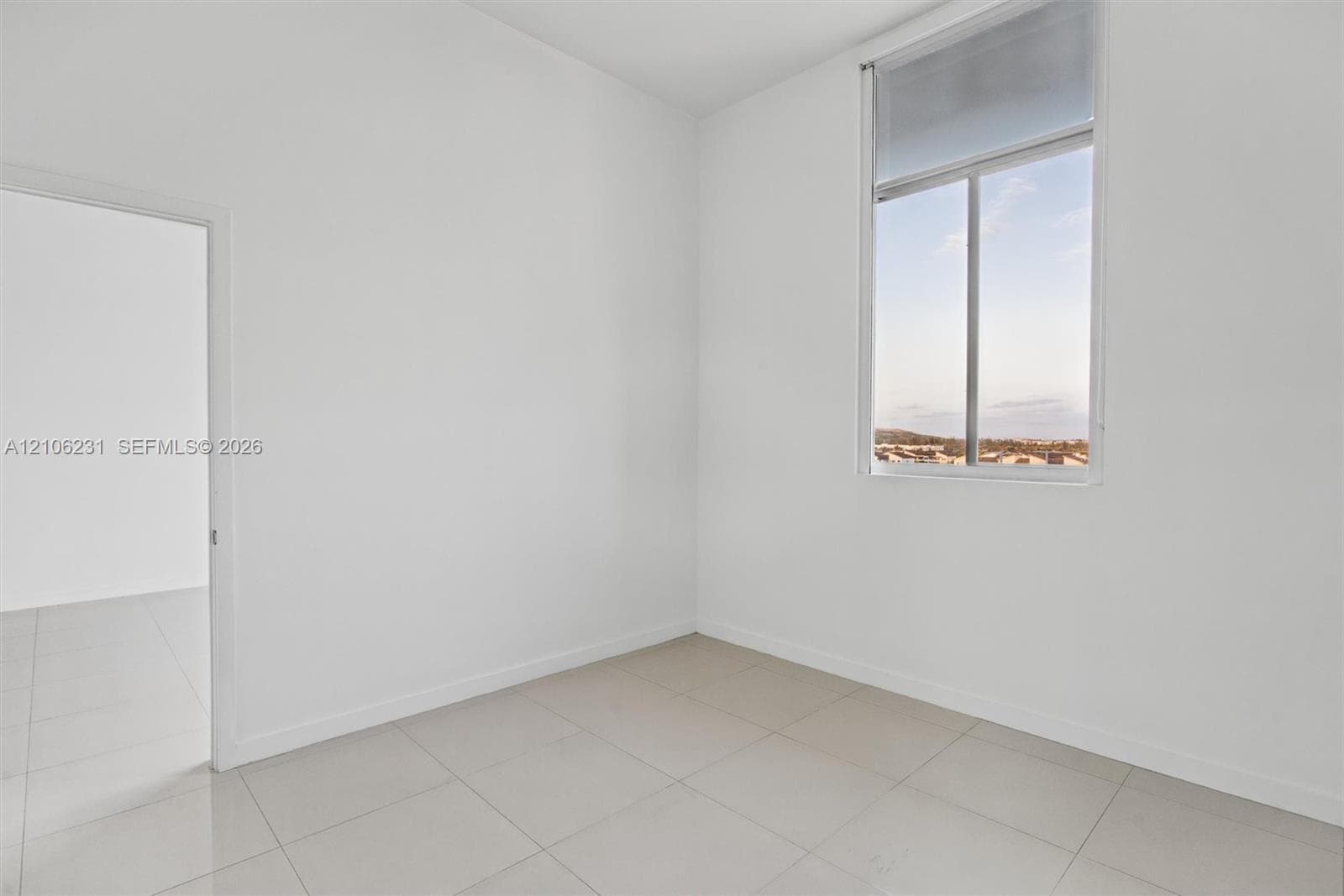 Bedroom with high ceilings, oversized window with exterior scenery, neutral walls, and 24x24 tile flooring