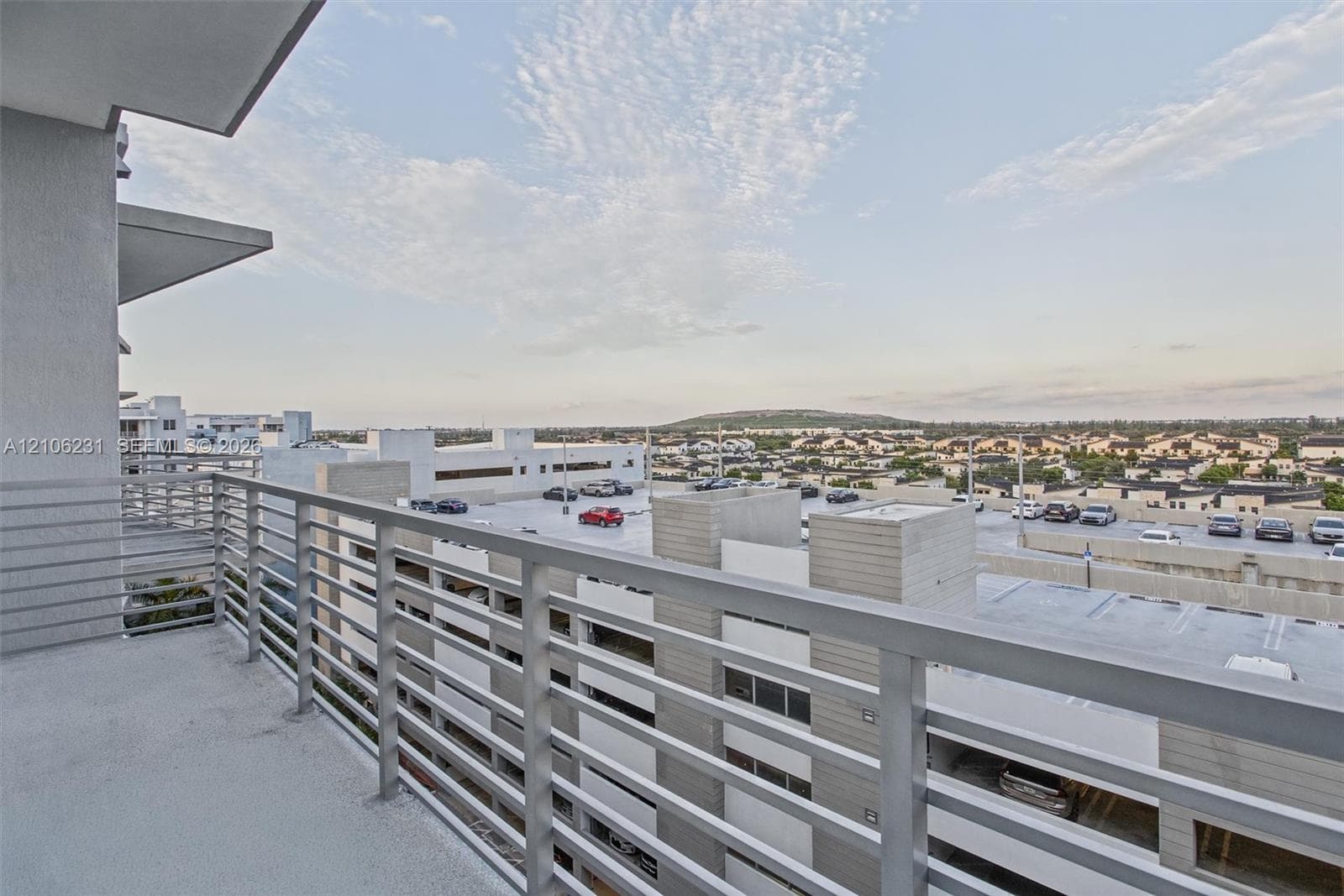 Private balcony featuring concrete flooring and a horizontal metal railing