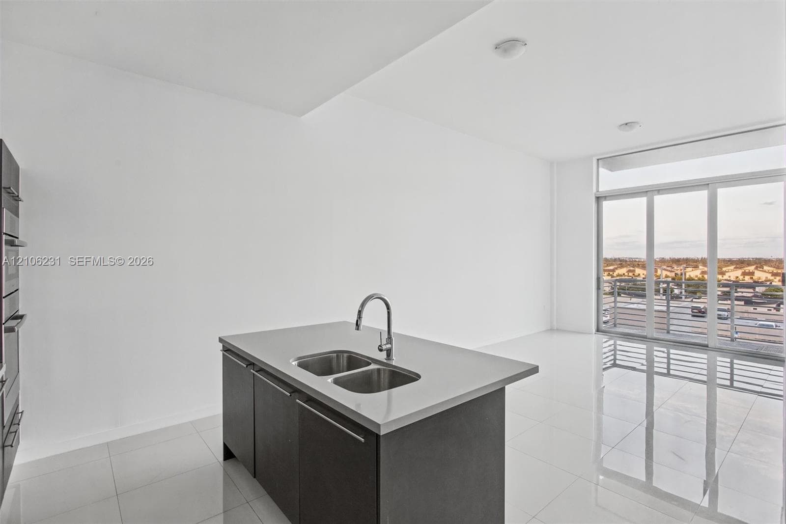 Kitchen island featuring a dual-basin stainless steel sink, solid surface countertop, and dark-toned cabinetry.
