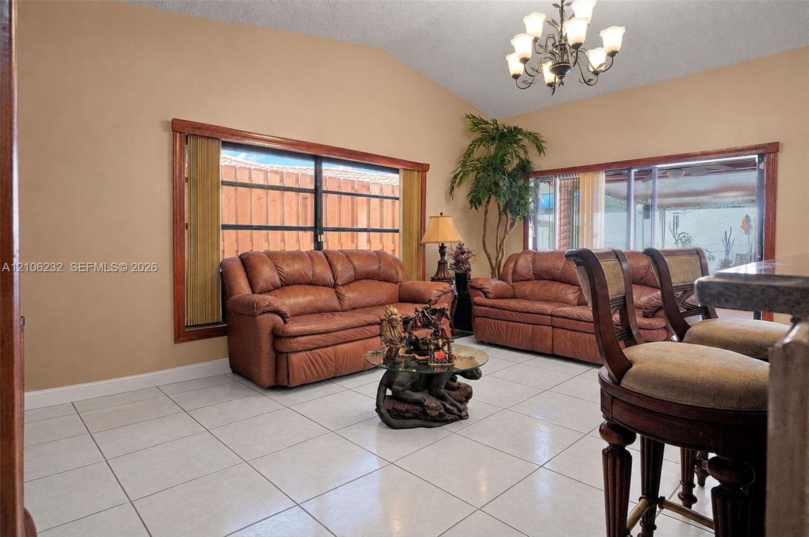 Vaulted ceilings, large windows with wood trim, ceramic tile flooring, and a multi-arm chandelier