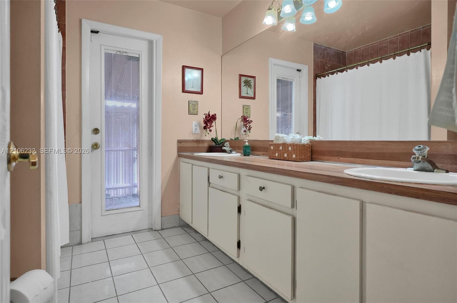 Dual vanity featuring white cabinetry, integrated sinks, a wood-finish countertop, full-width wall mirror, and ceramic tile flooring