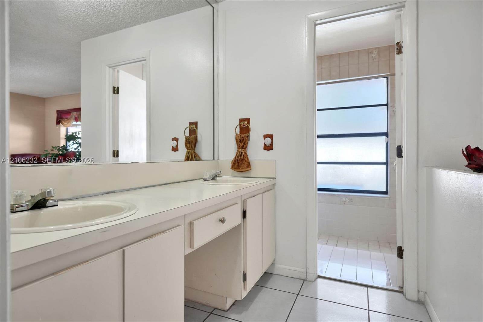 Bathroom vanity featuring a solid-surface countertop, dual drop-in basins, extensive wall-to-wall mirror, and neutral cabinetry