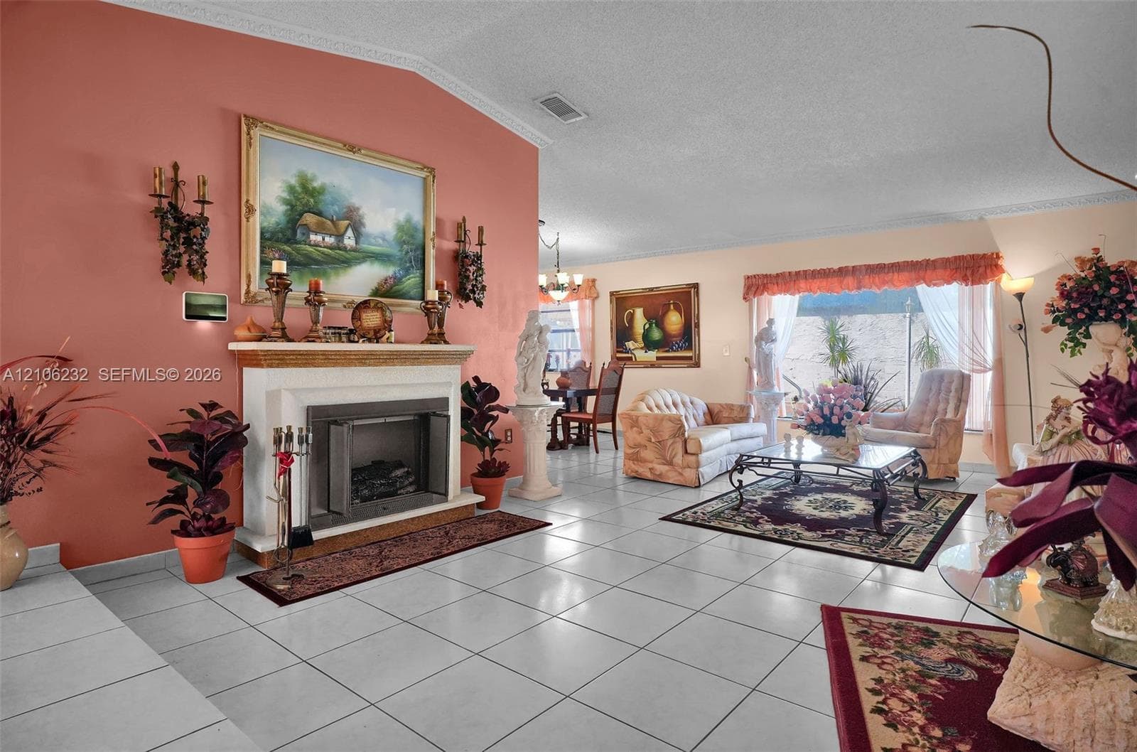Vaulted ceiling featuring crown molding, fireplace with an architectural surround, and large-format tile flooring