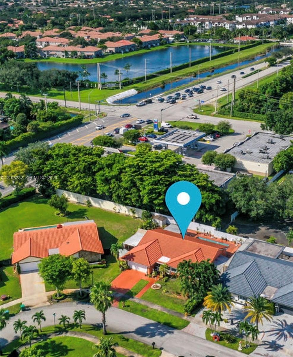 Aerial perspective featuring a terracotta-tiled roof, multi-car garage, and landscaped grounds with mature palm trees