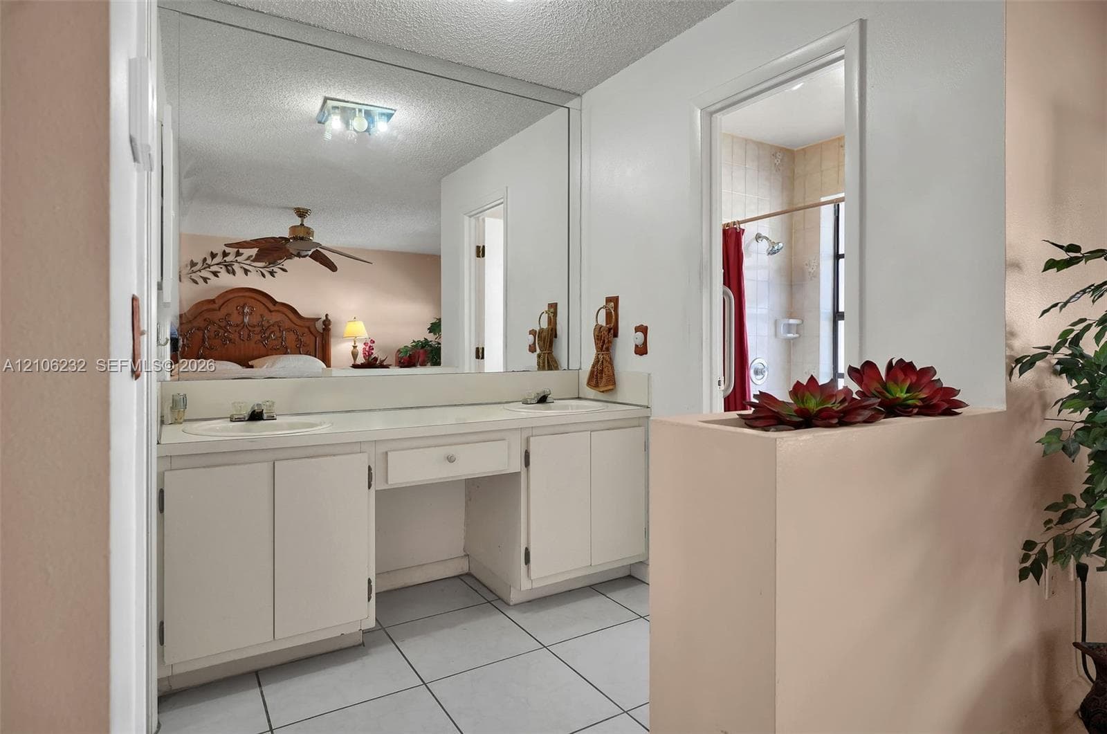 Dual-basin vanity featuring built-in cabinetry, an integrated countertop with drop-in sinks, a full-width wall mirror, and tile flooring