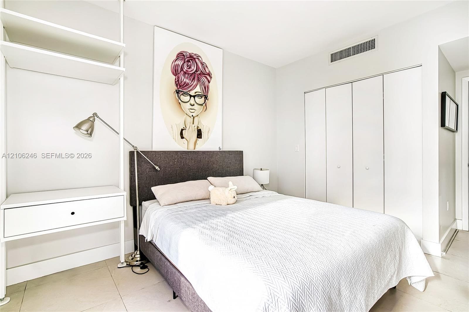 Built-in white shelving unit with integrated desk surface, tile flooring, and closet featuring white bifold doors