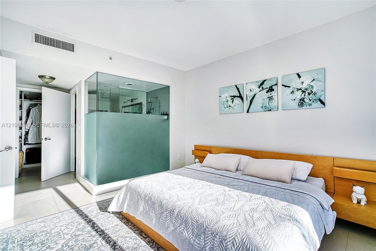 Glass-enclosed shower featuring a frosted privacy panel, built-in wooden headboard with integrated shelving, and large-format tile flooring