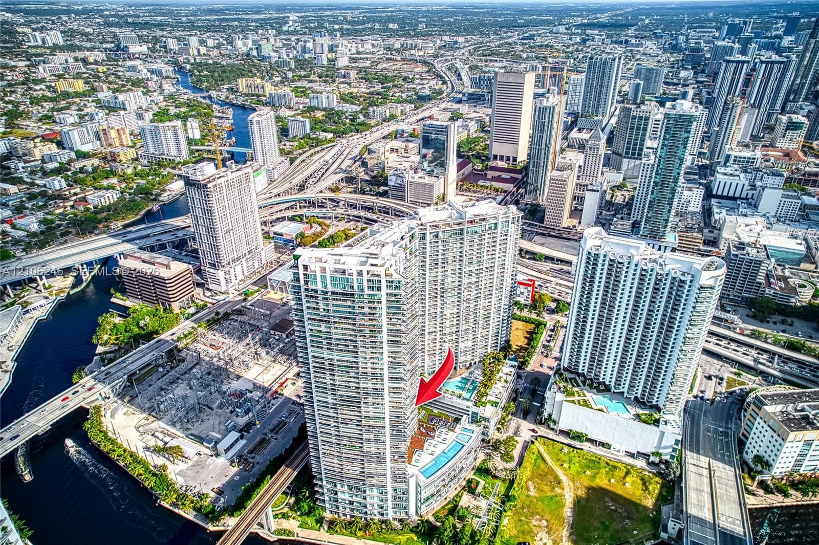 Aerial perspective of high-rise building featuring expansive balcony space, glass exterior cladding, and proximity to urban infrastructure and waterways
