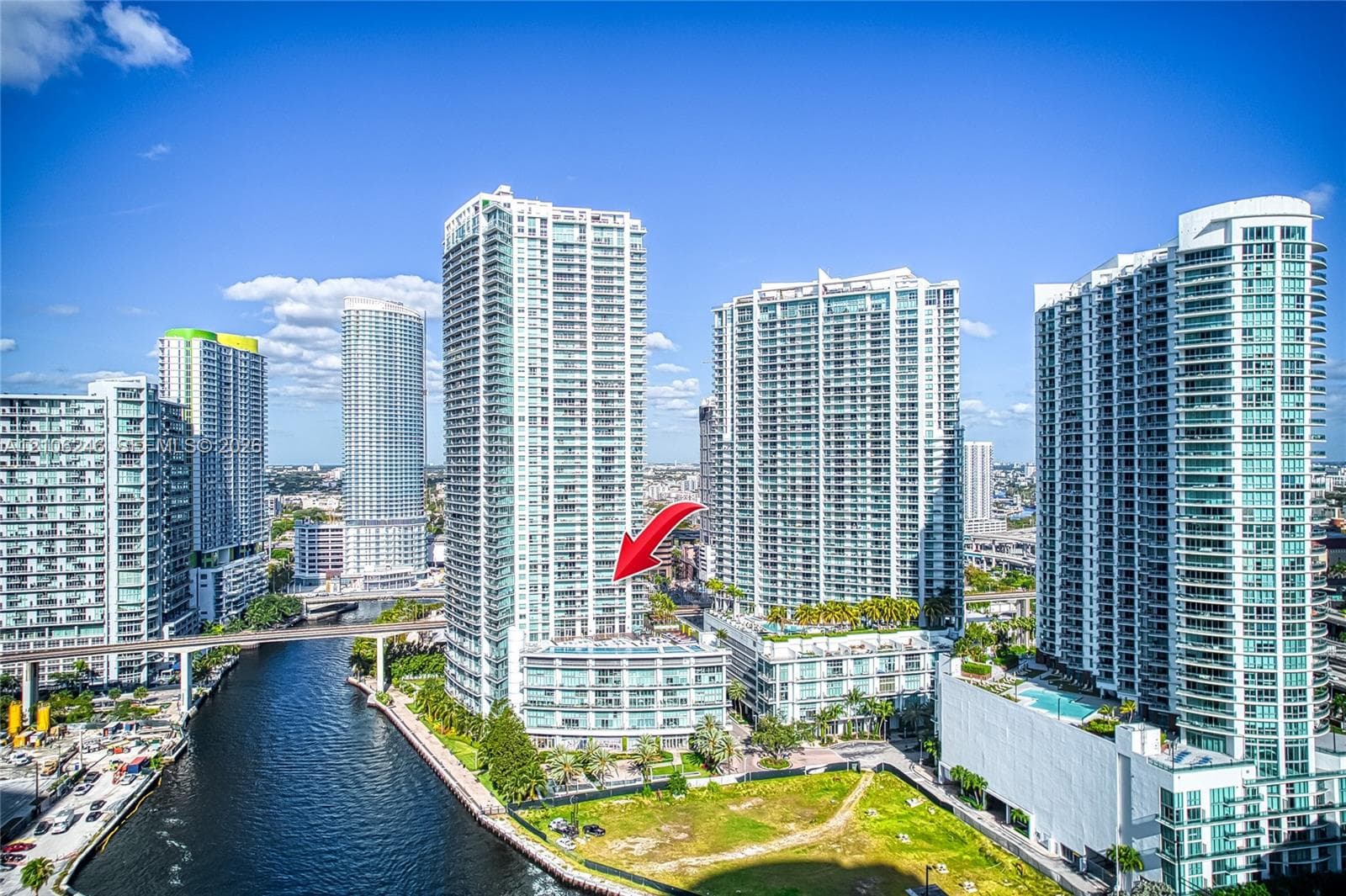 High-rise glass and concrete residential tower featuring private balconies, multi-story podium architecture, and waterfront positioning