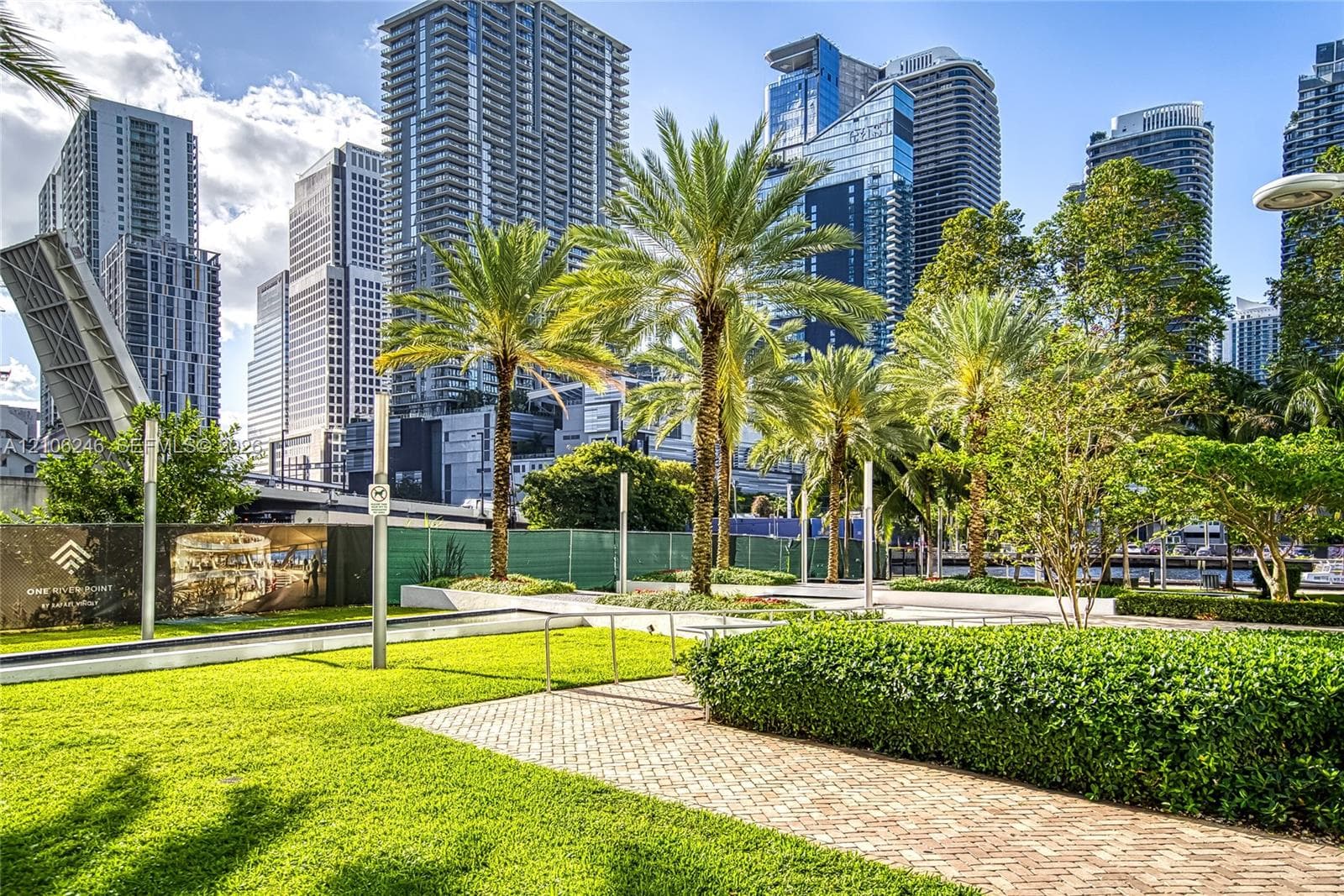 Landscaped outdoor grounds featuring a manicured lawn, palm trees, clipped hedges, and brick paver walkways