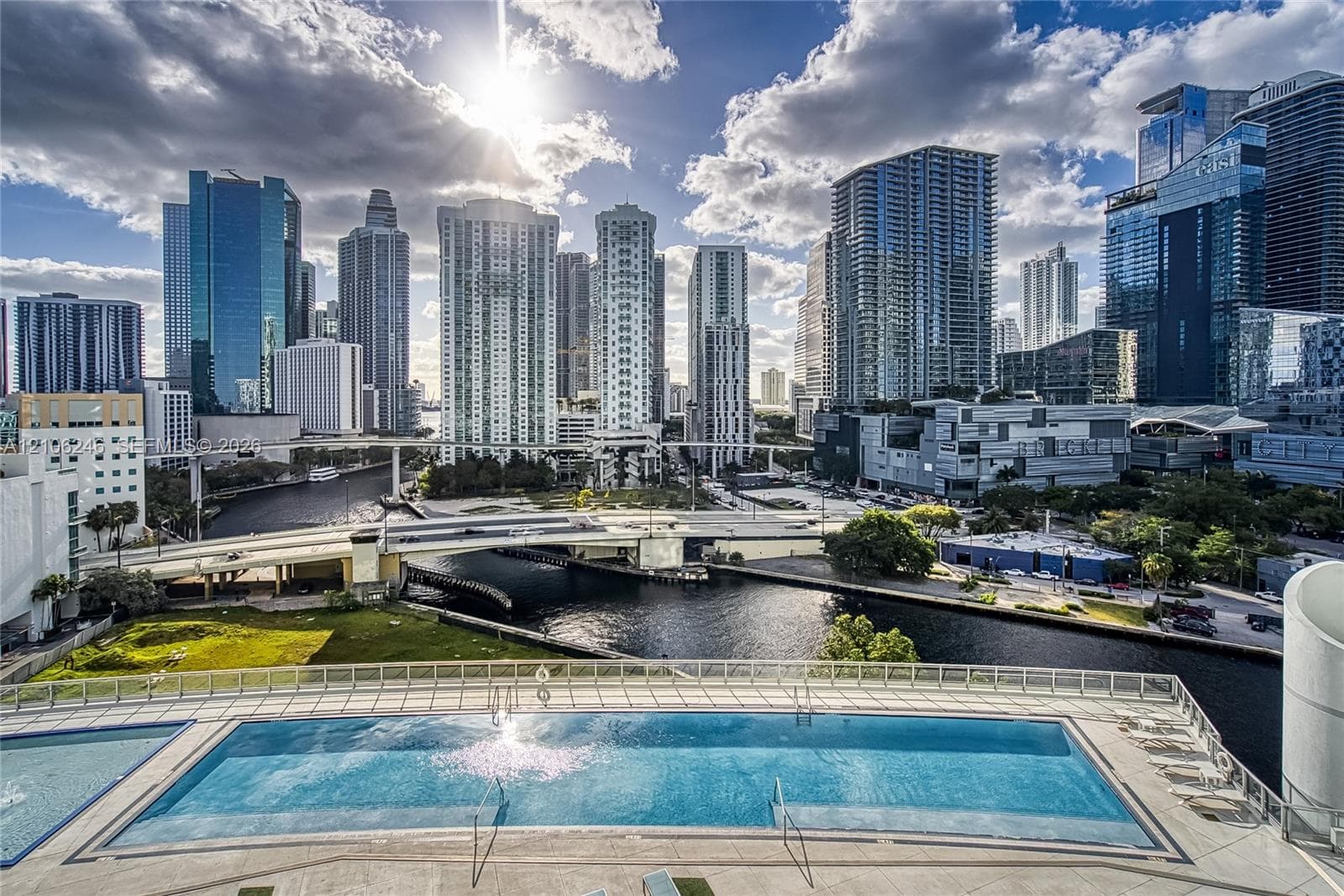 Swimming pool with a paved deck, glass railing, and prominent metropolitan skyline backdrop