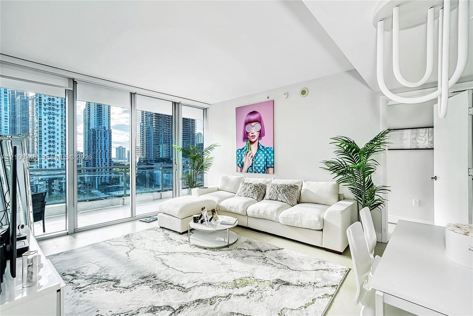Floor-to-ceiling glass wall, private balcony with glass railing, large-format tile flooring, and contemporary sculptural lighting fixture