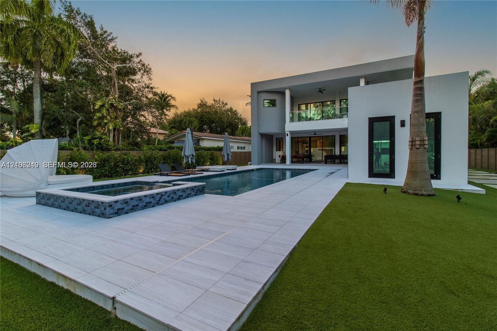 Modern exterior featuring a two-story architectural design, private swimming pool with integrated spa, large-format tile decking, and a maintained artificial turf lawn