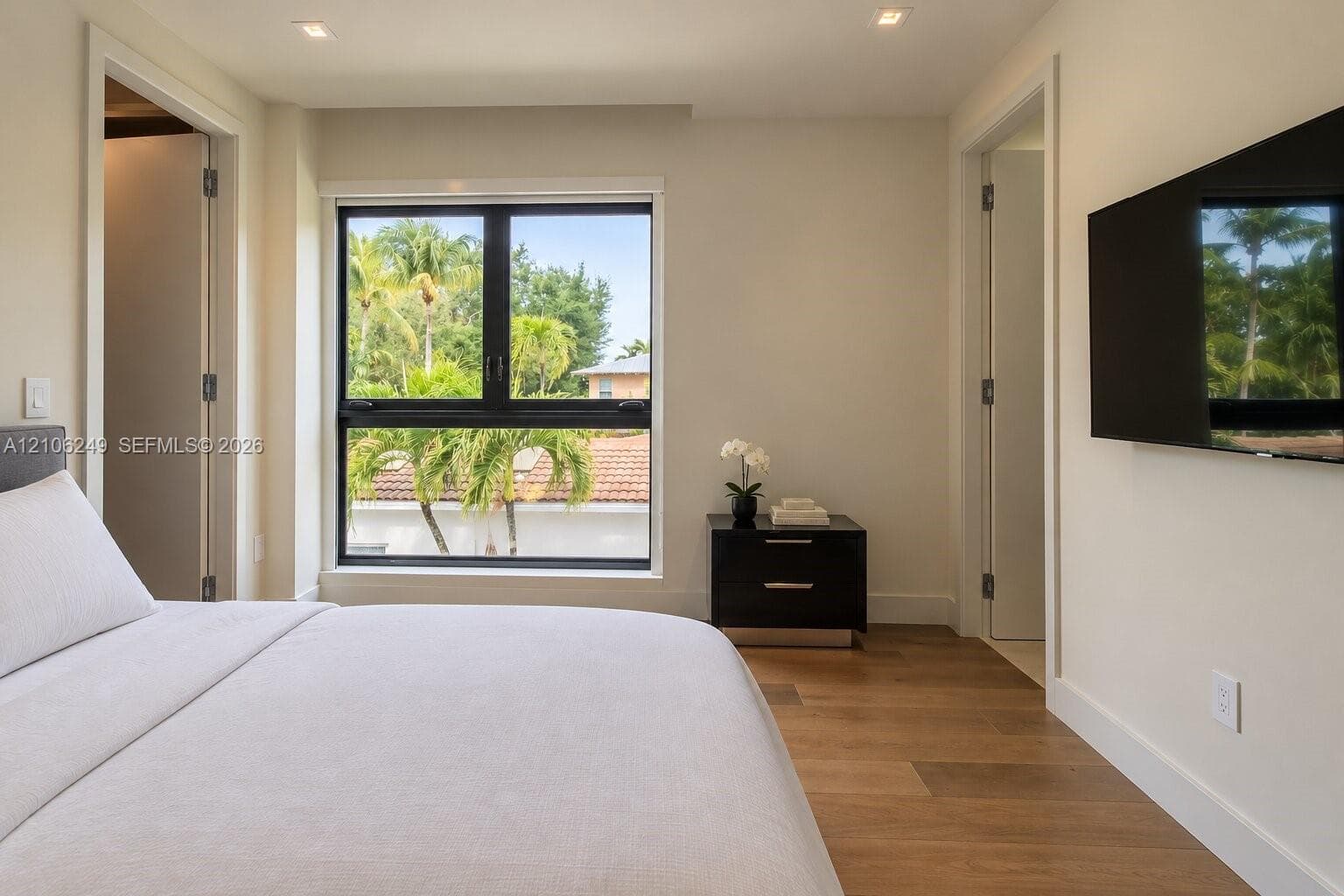 Neutral-toned interior featuring wood-finish flooring, recessed lighting, and a large black-framed window
