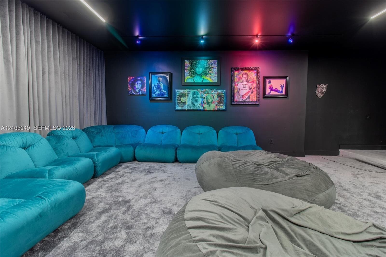 Media room featuring a matte black ceiling and accent wall, integrated track lighting, and full-height floor-to-ceiling drapery