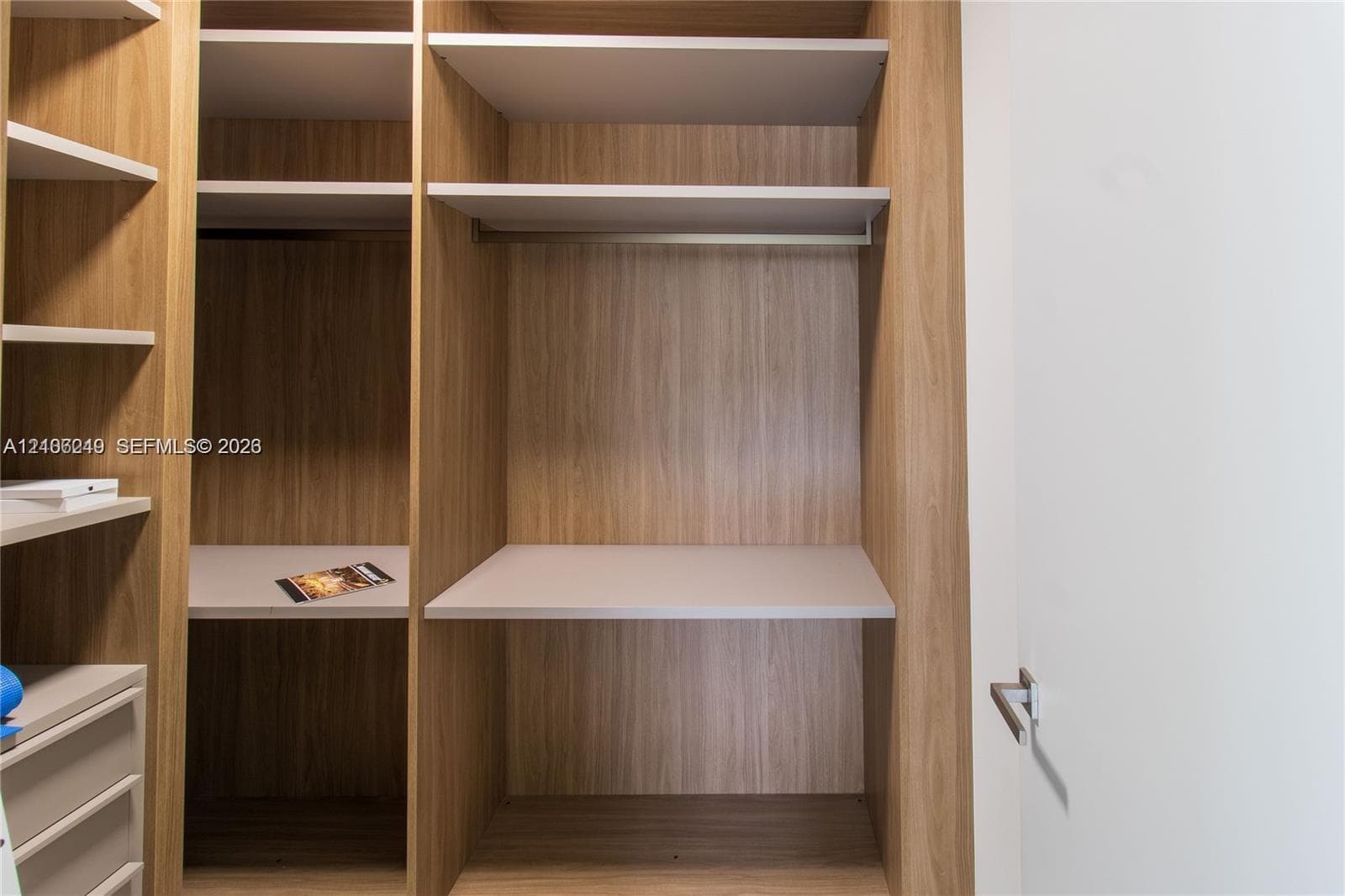 Custom wood-finish closet system featuring integrated shelving, hanging rods, and built-in drawer units with a flat-panel design
