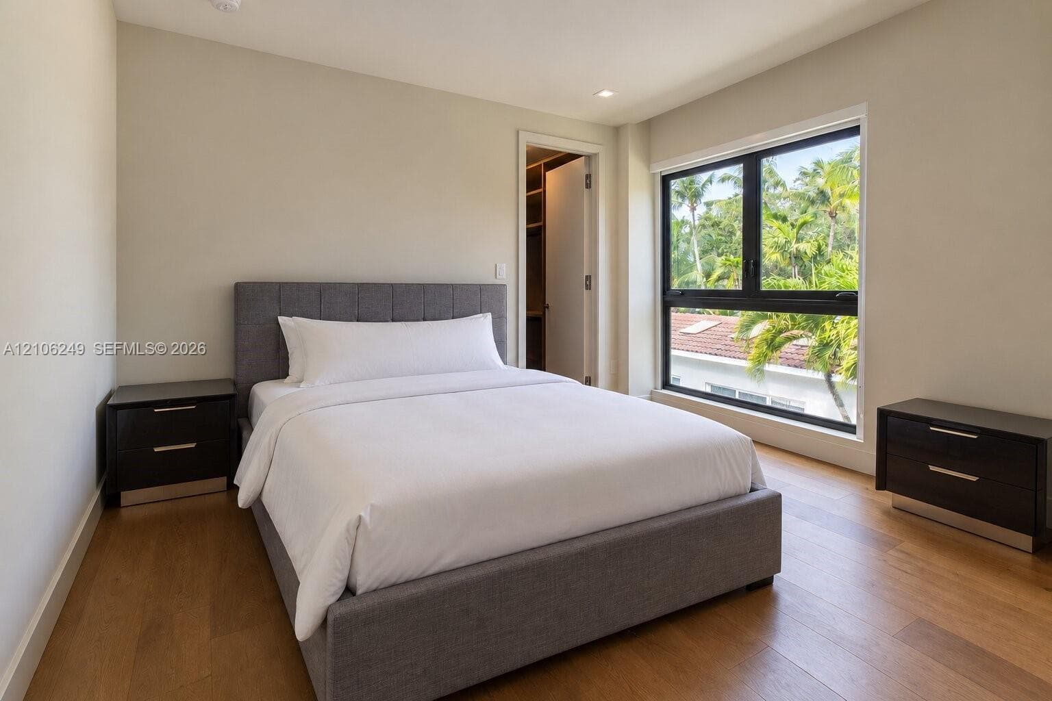 Room featuring wood-finish flooring, recessed lighting, a walk-in closet, and a large window with black framing